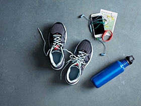 A pair of Training Shoes with a Water Bottle, a Phone and Headphones