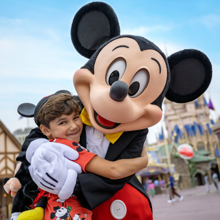 Mickey Mouse Hugging a Small Boy Wearing Mickey Ears