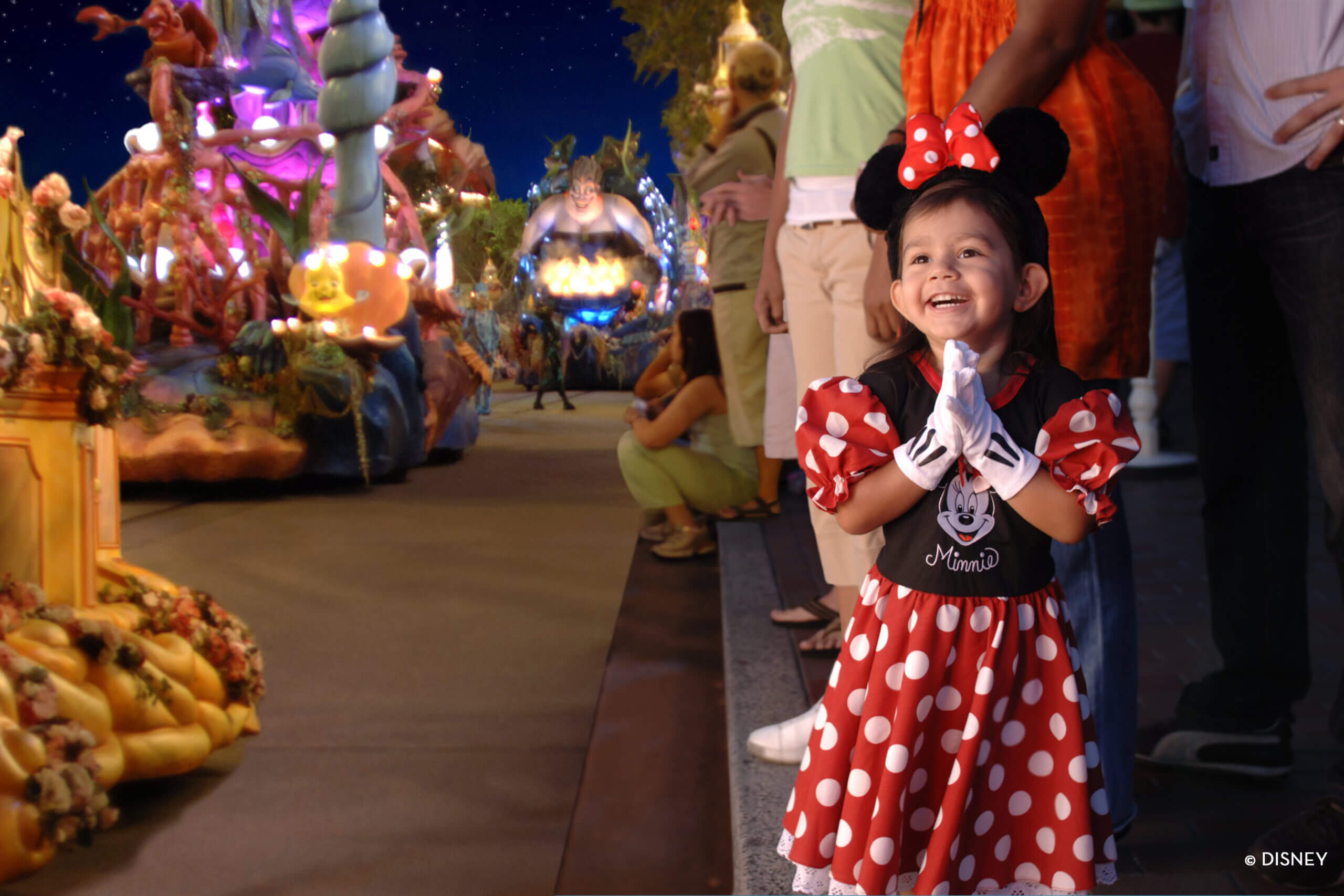 Little girl in Minnie Mouse costume watching parade