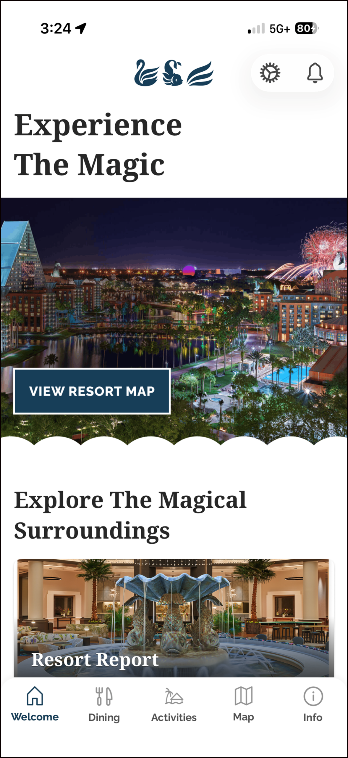 Mobile app screen showing a nighttime resort view with fireworks, the text “Experience The Magic,” and a button labeled “View Resort Map.” Below is a section titled “Explore The Magical Surroundings” with a Resort Report image.