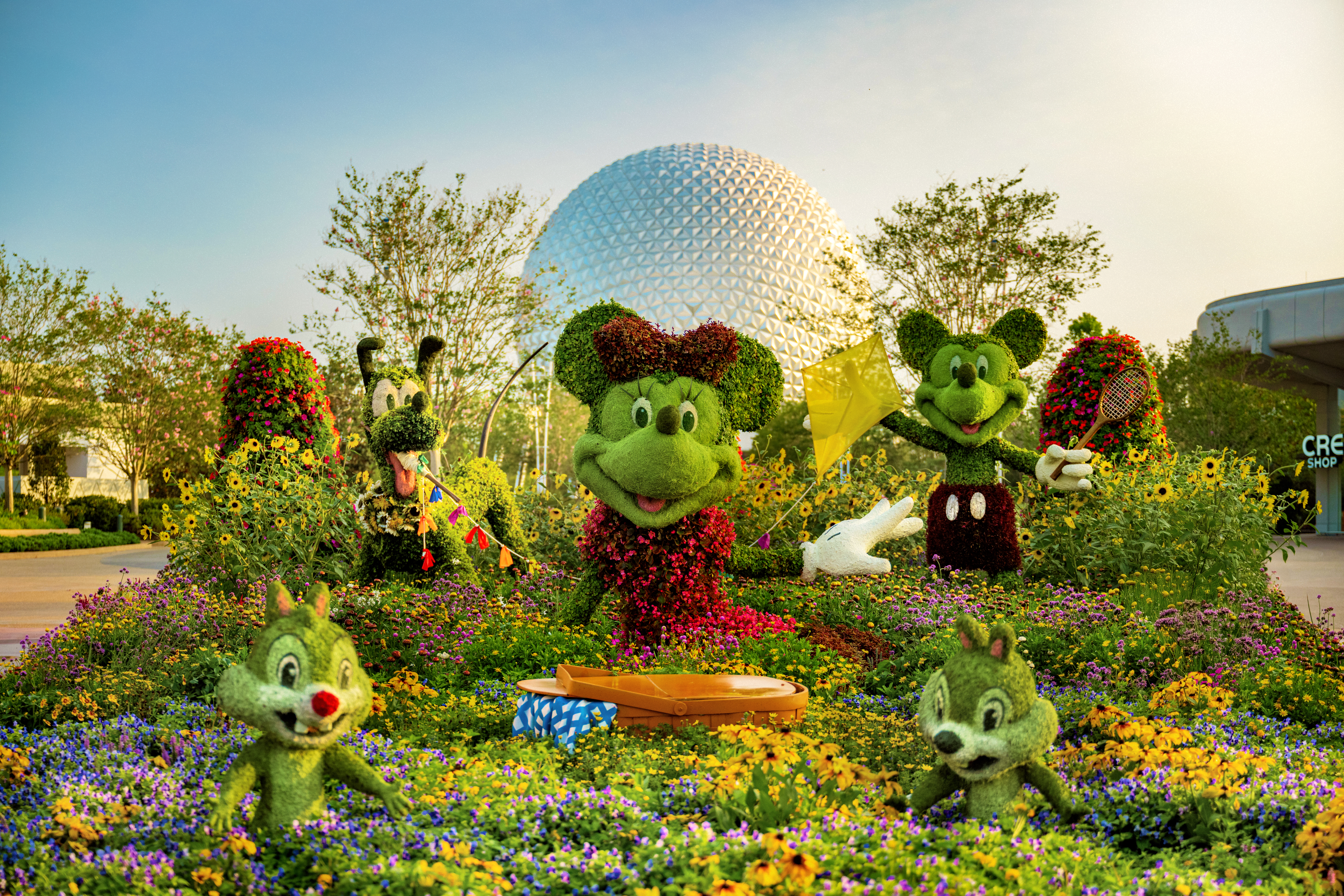 Disney character topiary in front of the EPCOT ball.