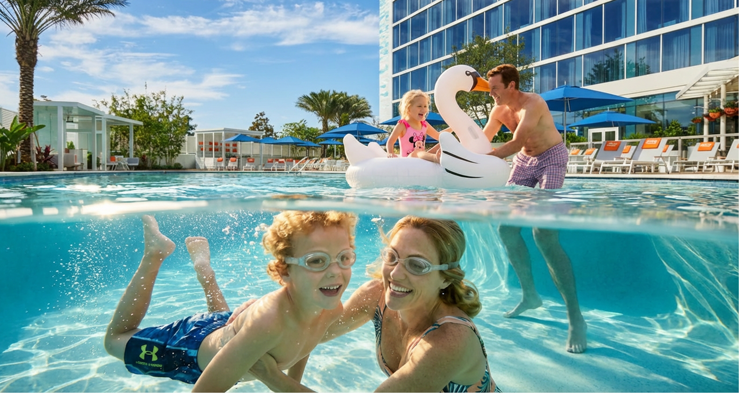 Two children and two adults enjoy a pool; two are swimming underwater with goggles, while the other two play with an inflatable swan float above water near a hotel with blue umbrellas.