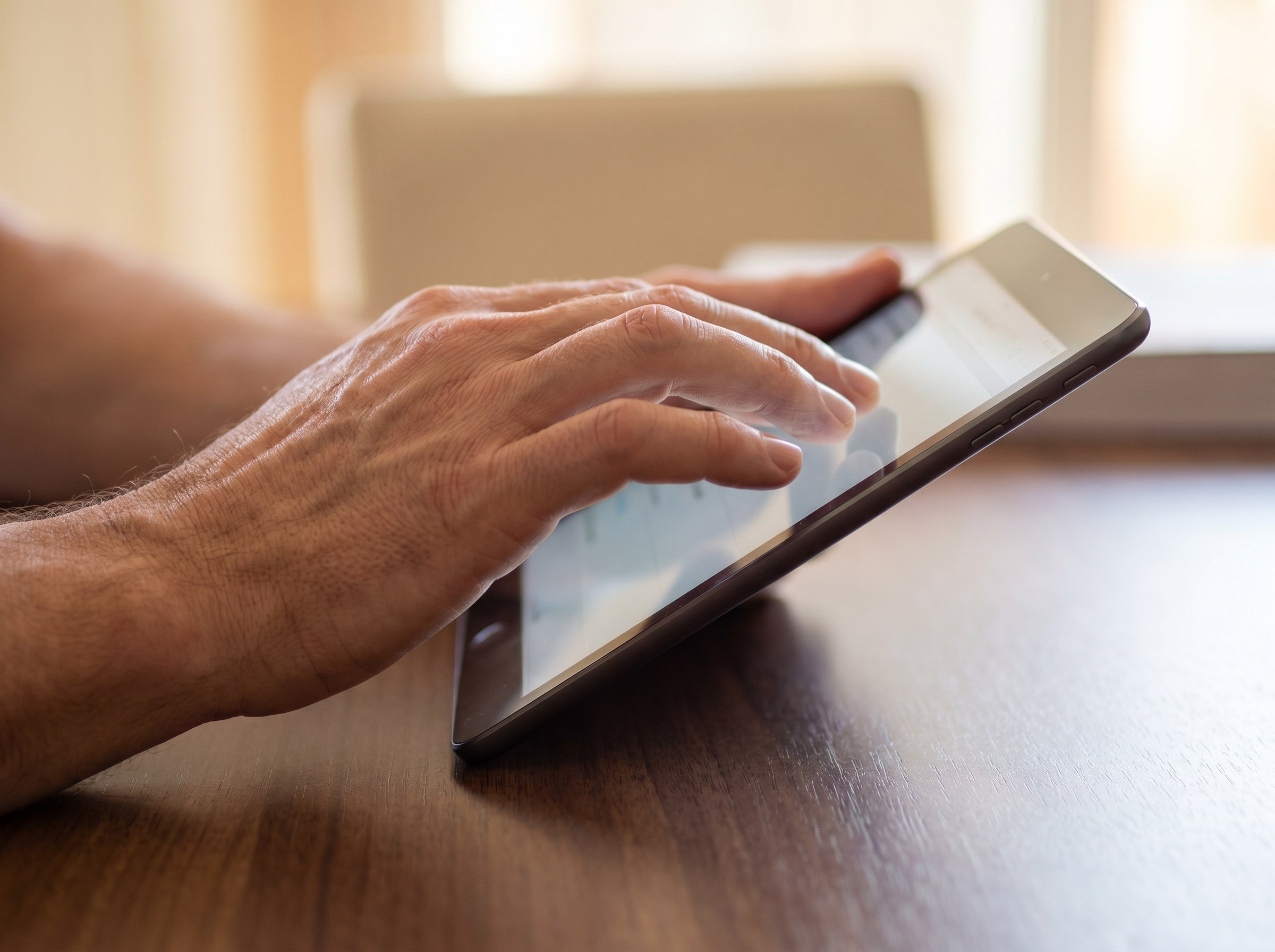 Hands holding a tablet showing a news site