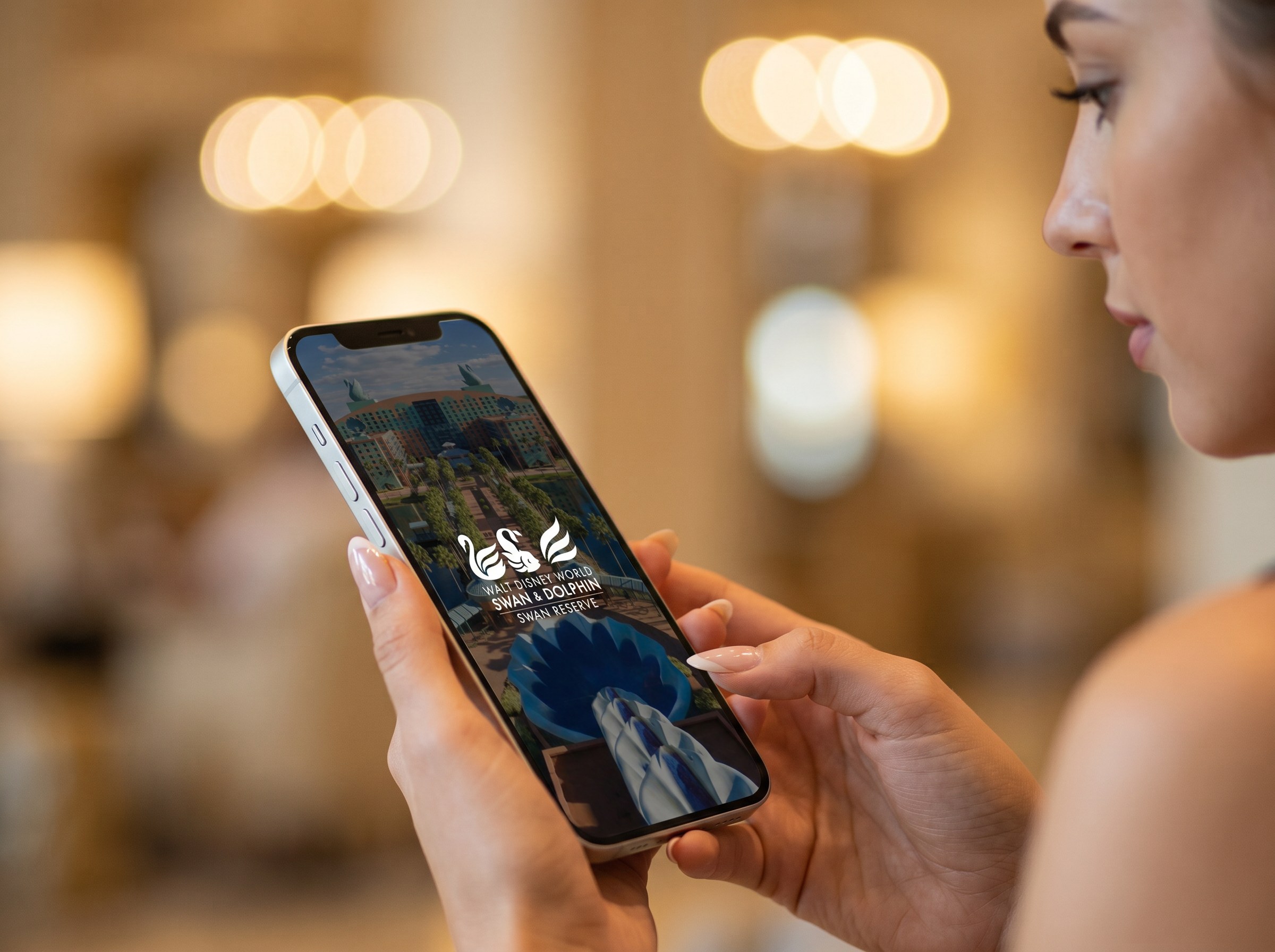 A guest holds a phone showing the resort app in a hotel lobby