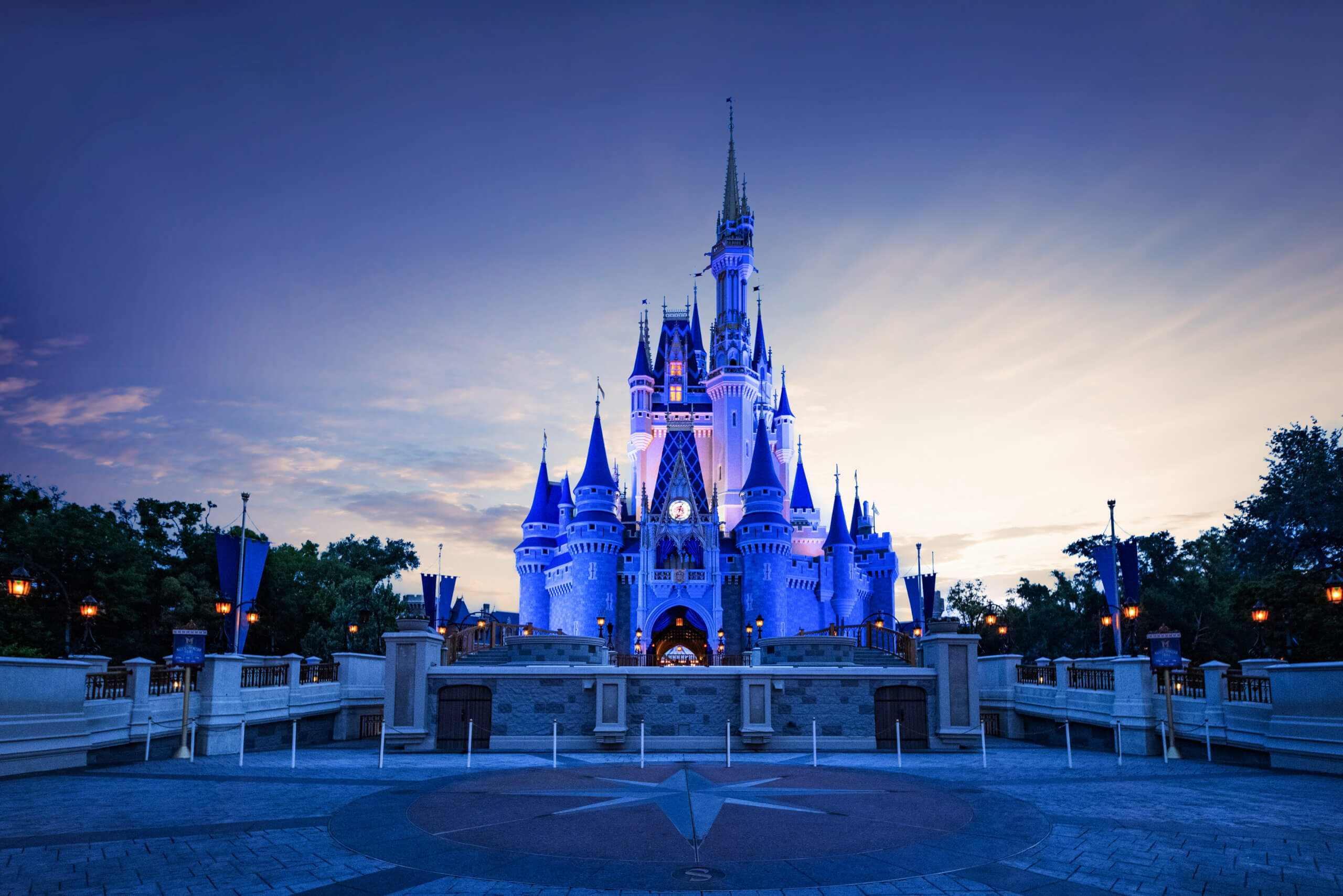 Cinderella Castle at Walt Disney World illuminated in blue light at dusk.